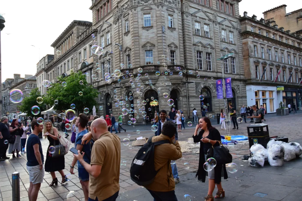Grupa ludzi na ulicy pomiędzy bańkami mydlanymi